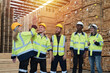 © amorn - Group of male and female warehouse workers standing putting their hands together in industry factory. Warehouse workers stack of hands in factory. Unity and teamwork concept