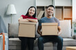 © NINENII - young couple helps put things in boxes and prepares, smiling happy moving to a new house.