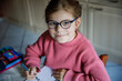 Portrait of happy little girl doing homework at home. Elementary school studing writing and learning. Smiling child writing letters, learing to write.