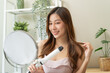 women hairdo makeup routine, Young woman looking at the mirror and using iron hair curling curly long hair at home.