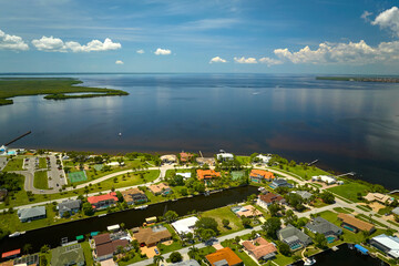 Wall Mural - Aerial view of residential suburbs with private homes located on gulf coast near wildlife wetlands with green vegetation on sea shore. Living close to nature concept