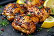 Grilled herb-marinated chicken thighs with lemon slices on a slate background, ideal for summer barbecues and healthy eating concepts