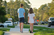 © bilanol - Rear view of two young teenage children, girl and boy, brother and sister walking together on rural street on bright sunny day. Vacation time concept