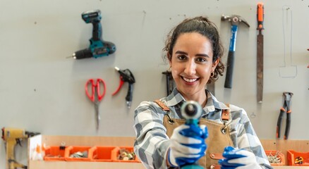 One Strong confident young aged women carpenter standing look at camera in workshop. Latin female carpenter entrepreneur working with wood plank furniture tool in workbench shop carpentry