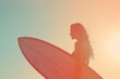 © Cheetose - Young woman holding surfboard on beach at sunset enjoying freedom and healthy lifestyle