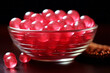 A glass bowl on a table filled with red chewing jelly candies on black background closeup shot. Sweet snack dessert