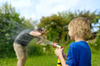 © Maria Sbytova - Funny little boy with his father playing with garden hose in sunny backyard. Preschooler child having fun with spray of water. Summer outdoors activity for kids.