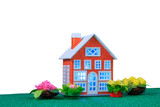 Fototapeta Tęcza - A small red house with blue light in the windows surrounded by flowers