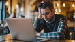 © Sol Revolver Group - Young Man Feeling Stressed While Working on Laptop in Busy Cafe