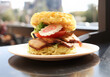 A delicious-looking ramen burger with a fried egg, tomato, lettuce, and bacon
