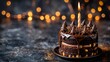   A chocolate cake atop a plate, smothered in chocolate frosting, with a lit candle crowning it