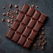 Whole milk chocolate bar with broken pieces on a dark slate background, flat lay
