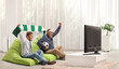 Men at home cheering with a scarf and ball, sitting on a bean bag armchairs