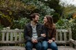 © Iftikhar alam - A man and a woman sit on a wooden bench, laughing together, A couple laughing together as they sit on a rustic bench in a picturesque park