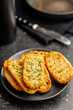 Garlic crisp bread Slices Topped With Herbs onn plate on black table.