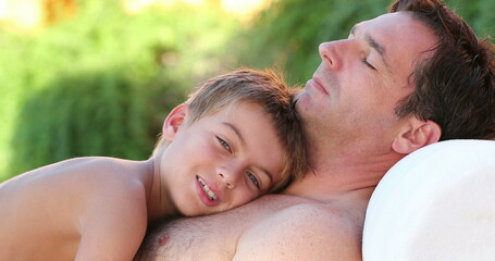 Wall Mural - Father and son together small boy laid on dad chest outside