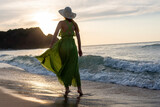 Fototapeta Zachód słońca - Happy woman walking on beach at sunset.Beautiful female happy relax walking on beach near sea when sunset in evening.