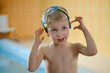 © ninelutsk - Happy cute toddler child near the pool side smiling in goggles after swimming lesson indoor. Physical development and healthy water activities for kids
