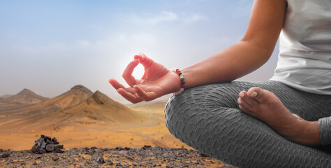 Wall Mural - Woman meditating in yoga position with desert background