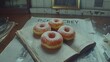   A pair of donuts perched atop a novel on a table adjacent to a mug of joe