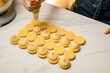 Pastry chef decorates a macarons with thick cream on a smooth table
