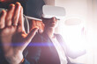 Young woman in suit wearing virtual reality headset in airplane and gesturing with hands to control simulation of 3D futuristic dimension.Contemporary advanced technology and innovation. Female use VR