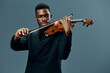 Elegant African American musician playing the violin in a formal black suit on a neutral gray background