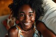 Cheerful young african woman with vitiligo smiling at camera relaxing on sofa at home.