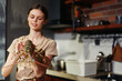 A woman holding a lobster in front of a kitchen in a seafood cooking concept