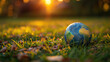 Small Globe Resting on Green Grass With Sunset Light Shining Through, Symbolizing Earth Day