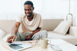 © SHOTPRIME STUDIO - Tired African American Freelancer Working on Laptop in a Sad and Unhappy State of Mind Sitting on a Sofa in a Modern Home