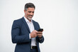 © Stock 4 You - Mature businessman in suit holding cellphone isolated, white background. Smiling Latin business man using smartphone mobile phone screen device, scrolling app, working for communication, copy space