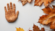 A hand is placed on top of a pile of autumn leaves