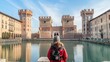 Tourist woman visiting the Ferrara castle of Italy. Surrounded by wide moat filled with water, which gives it a sense of isolation