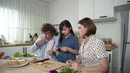 Wall Mural - Happy caucasian father and mother sitting and eating fruit at modern kitchen. Energetic family spend time together by enjoy eating fruit or healthy fruit with kitchenware and fruit on table. Pedagogy.