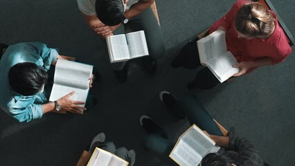 Wall Mural - Top down view of prayer reading at bible book and sitting in circle with bible book on laps. Aerial view of diverse people looking at book while studying with faith, trust and hope, calm. Symposium.