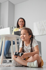 Poster - Little girl playing video game while her mother working at home