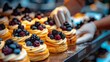   Close-up of a tray filled with pastries topped with juicy berries Hand extends, poised to pick one