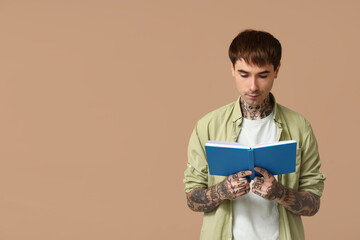 Poster - Young tattooed man reading book on brown background