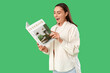 © Pixel-Shot - Young woman reading interior magazine on green background