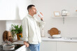 © Pixel-Shot - Young man with bottle of tasty yogurt in kitchen