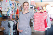 Pregnant woman in striped tunic chooses shirt in clothing shop