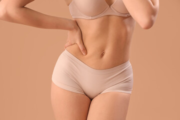 Sticker - Beautiful young woman in stylish beige underwear on brown background, closeup