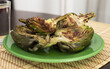 Cooked fried halves artichokes on green plate
