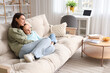 © Pixel-Shot - Happy mother with her little daughter watching TV on sofa at home