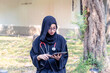 Young Asian beautiful woman Muslim medical student wearing traditional clothes relaxing with tablet in the hospital park.