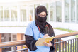 Female Muslim doctor in Abaya niqab traditional clothes works at modern clinic office checking of work list on clipboard with sun fare background.