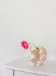 A pink tulip in a creative ceramic vase on a white table. Minimalism style home decor