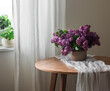 A cozy still life - a bouquet of lilacs on a muslin path on a round wooden table in the living room by the window