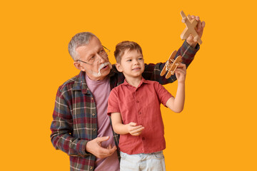 Poster - Grandfather and his happy cute little grandson playing with wooden toys on yellow background